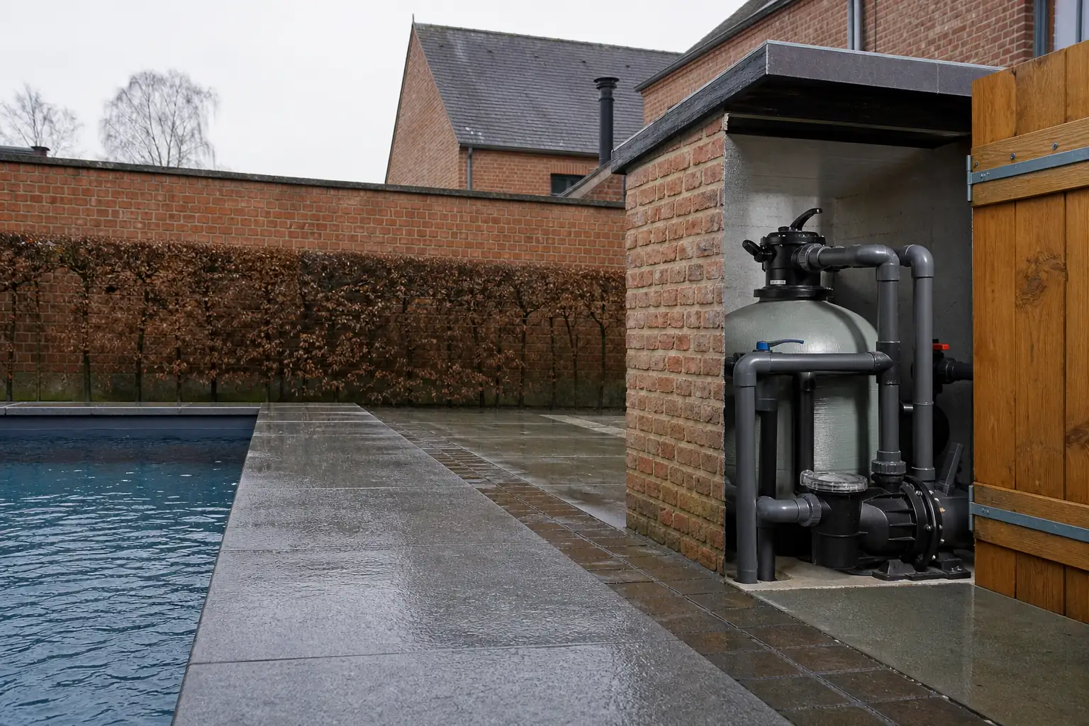Margelle d’une piscine enterrée et local technique ouvert laissant voir filtre et canalisations